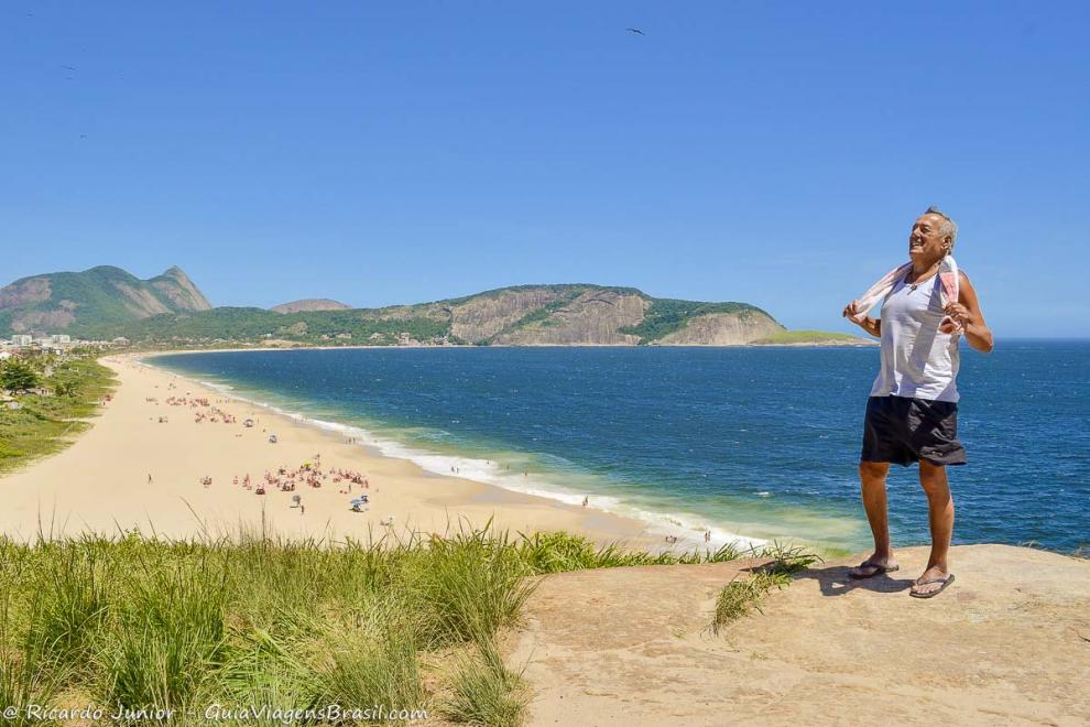 Imagem de um senhor rindo e aproveitando a bela vista da Praia de Camboinhas em Niterói.